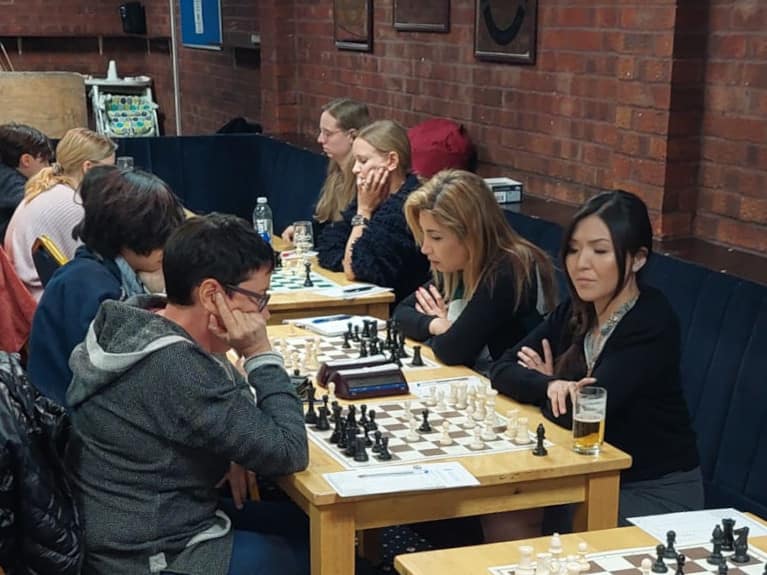 An image of eight women playing chess. In the foreground are Anuurai Sainbayar and Dina Ladnyuk.